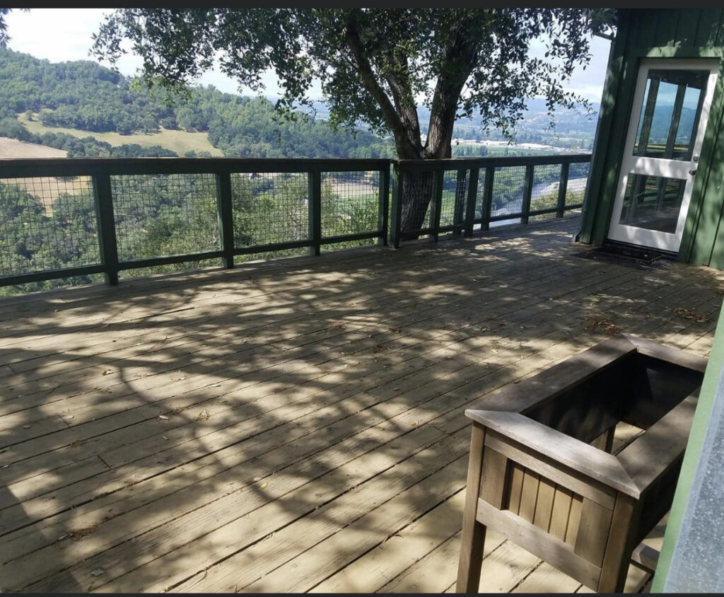 Wooden deck flooring with an outdoor railing and tree built in the center.